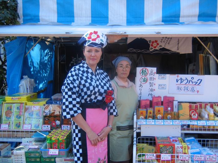 NHK TV reporter Judit Kawaguchi with a shop clerk on Izu Oshima island in Japan. Judit is dressed in the outfit worn for the island's camellia festival, called the Izu Oshima Tsubaki Matsuri. 